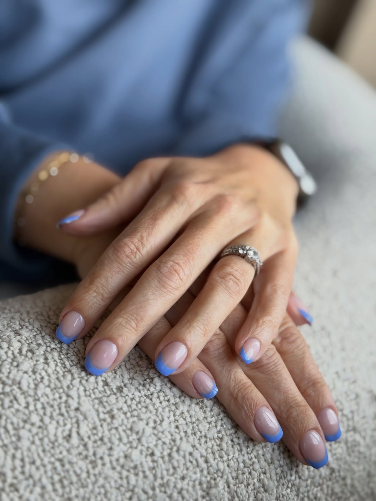 Cornflower-blue French tips on a sheer nude oval gel manicure